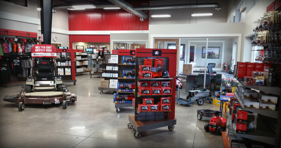 Parts showroom floor with a mower, apparel, and boxed accessories